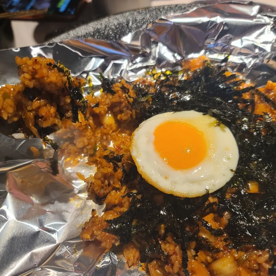 Kimchi fried rice stir-fried in foil on the cast-iron plate, topped with a soft-boiled fried egg