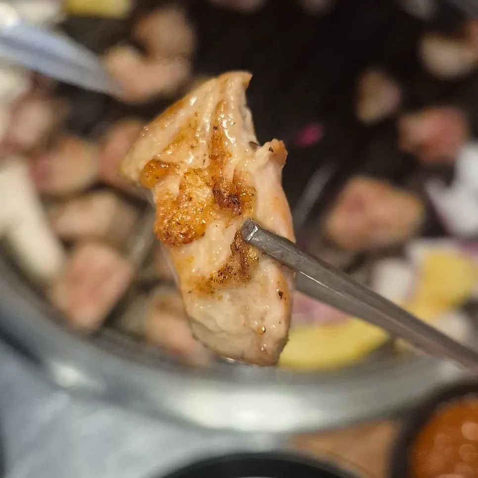 Bite-sized pork neck pieces cooking on the grill
