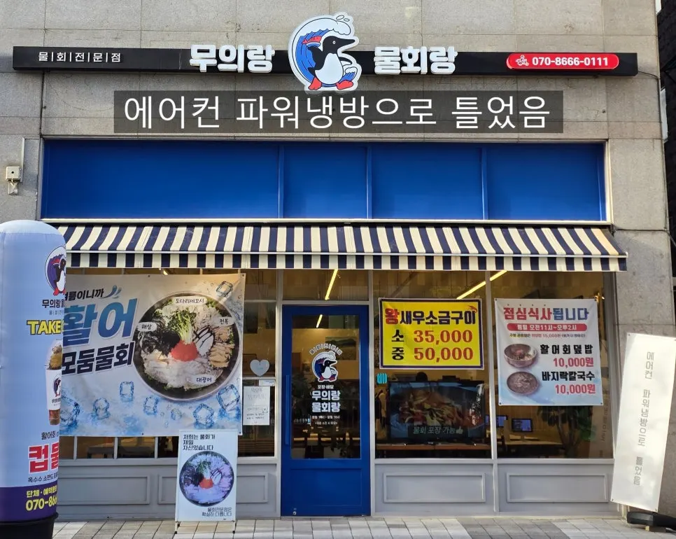 파란 어닝과 출입문이 보이는 물회 전문점 입구
