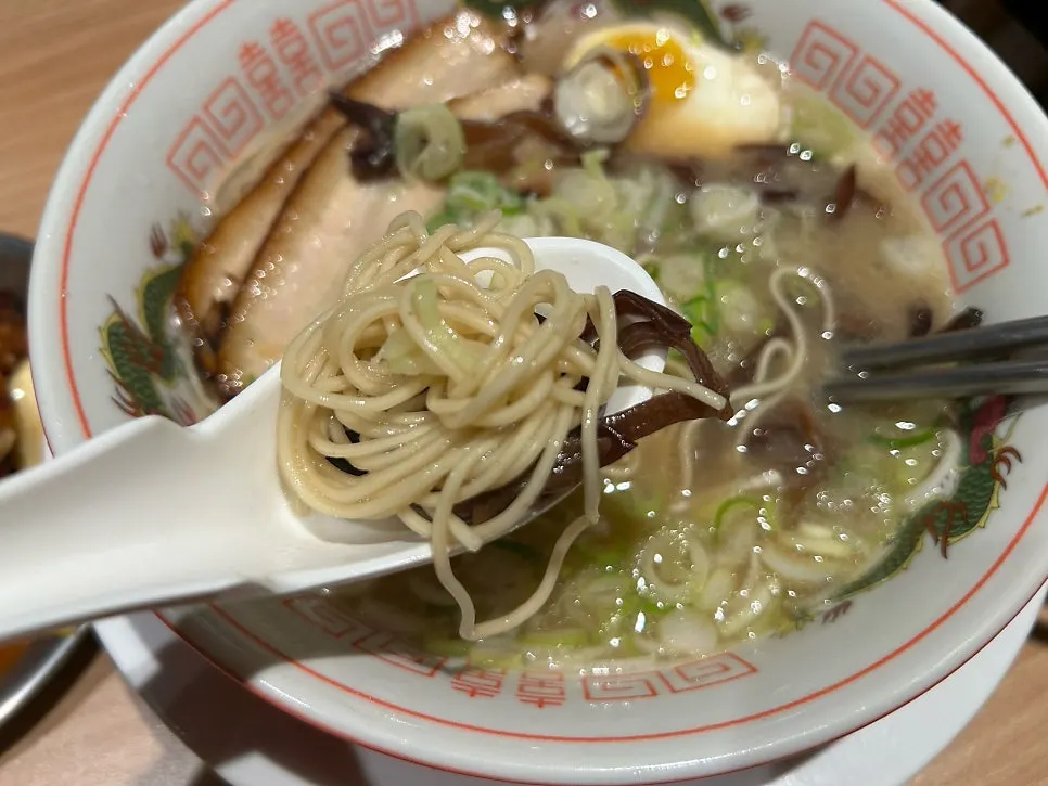 Tonkotsu ramen noodles lifted with chopsticks