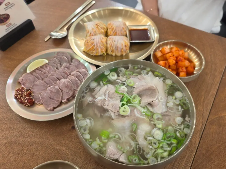 Full table spread of pork gomtang, cold jeyuk, and cabbage dumplings