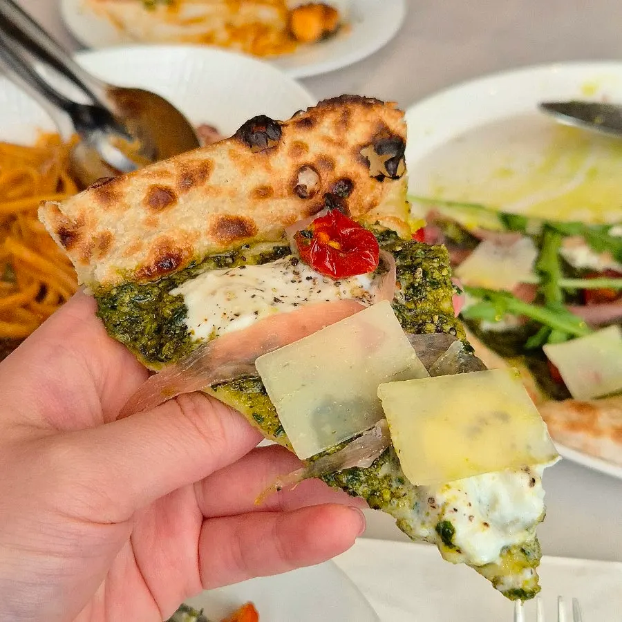 Basil burrata pizza picked up and eaten by hand