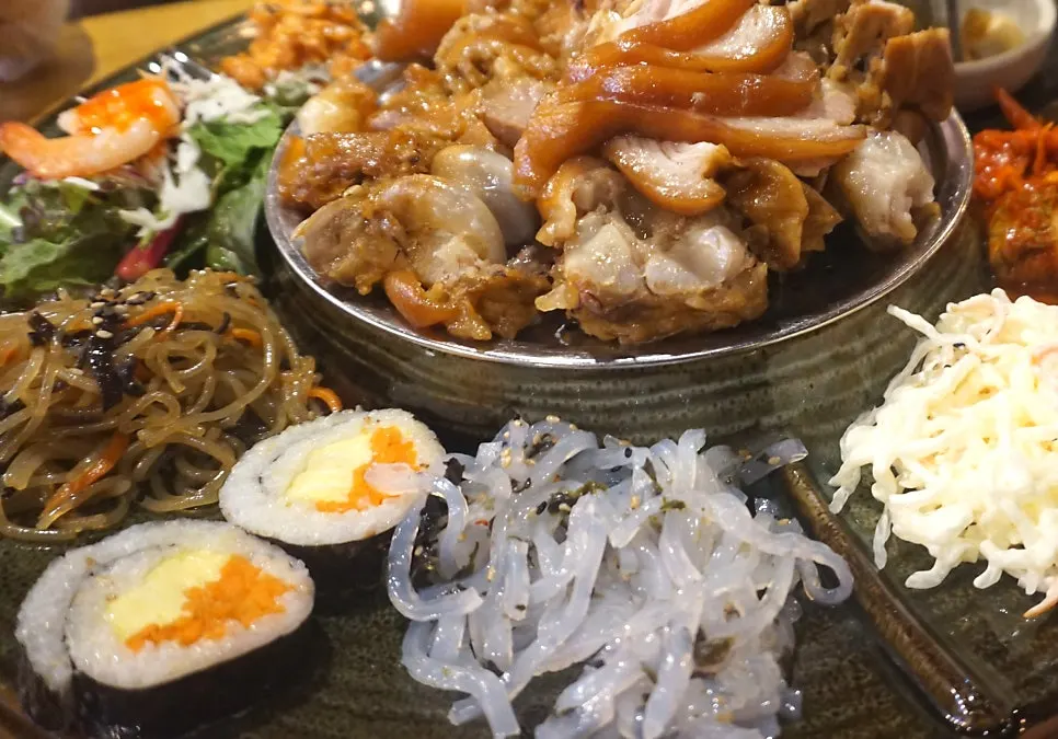 Side dishes including japchae, gimbap, and salad