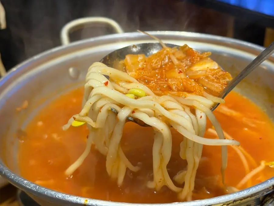 Kimchi kalguksu bubbling on the stove
