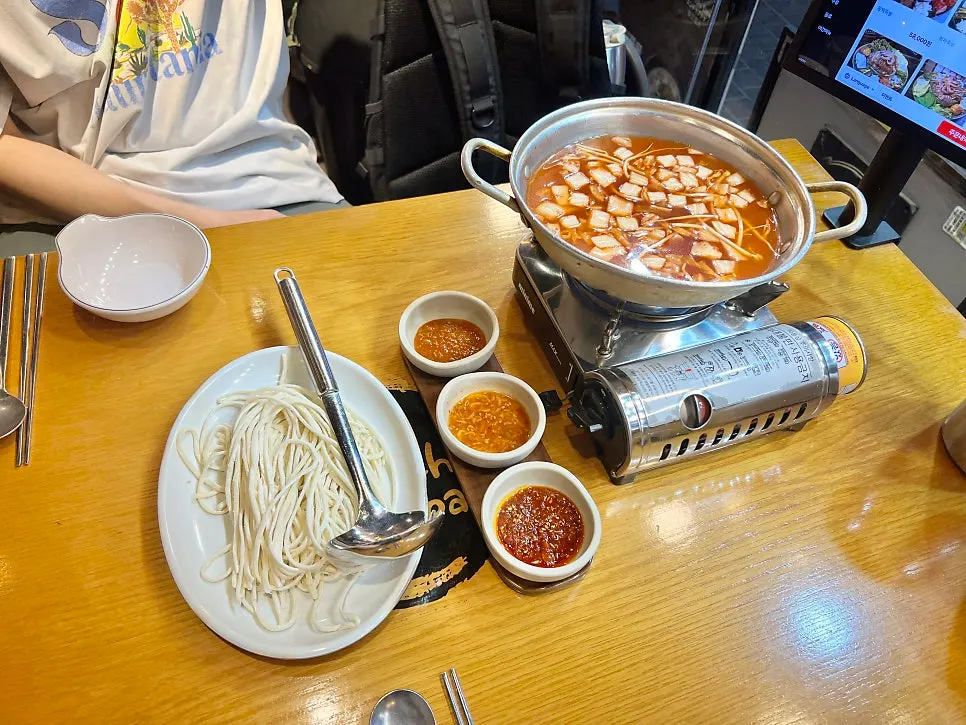 Pot of kimchi kalguksu served as a complimentary side dish
