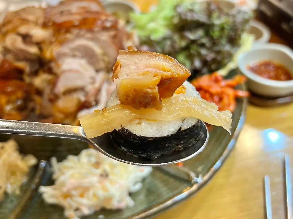 A bite of gimbap topped with baegmuk-eunji and jokbal