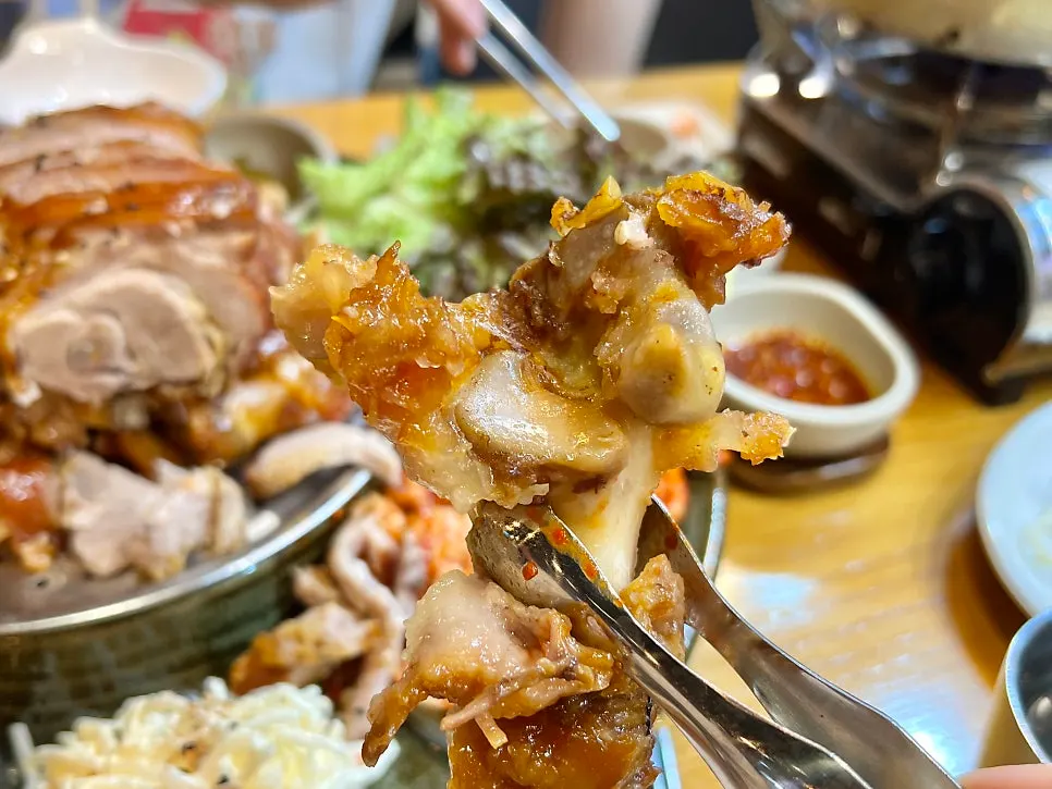 Holding a jokbal bone with tongs to pick apart the meat
