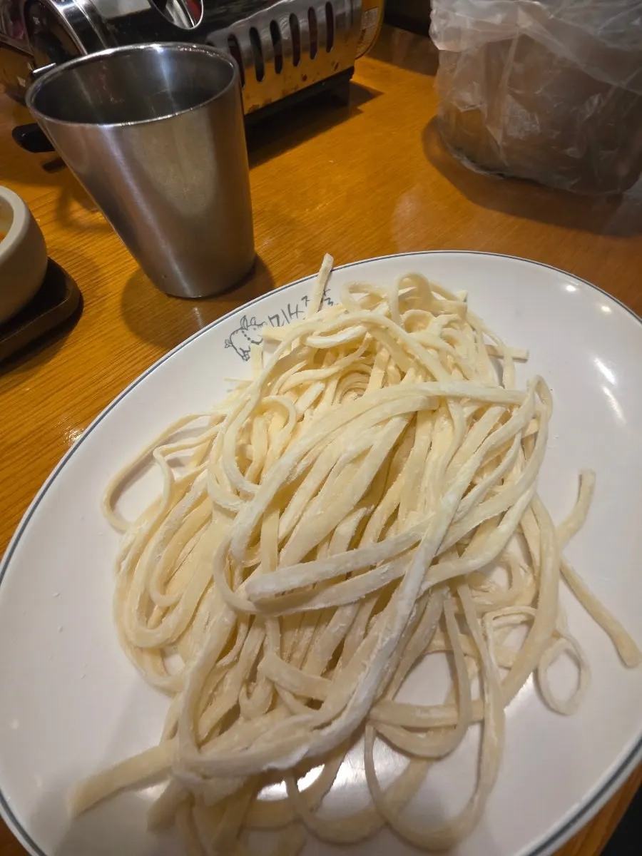 A bowl of kimchi kalguksu served with jokbal