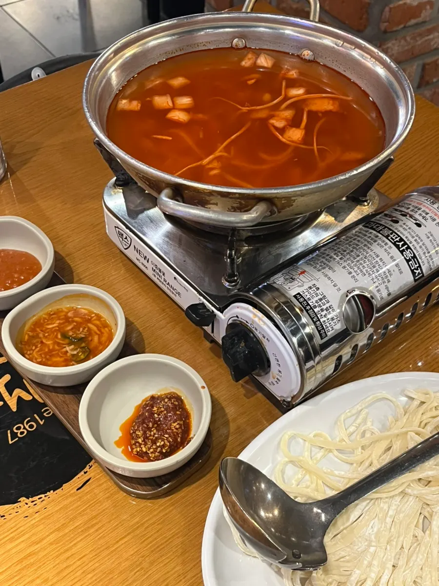 Kimchi kalguksu broth boiling on the tabletop burner