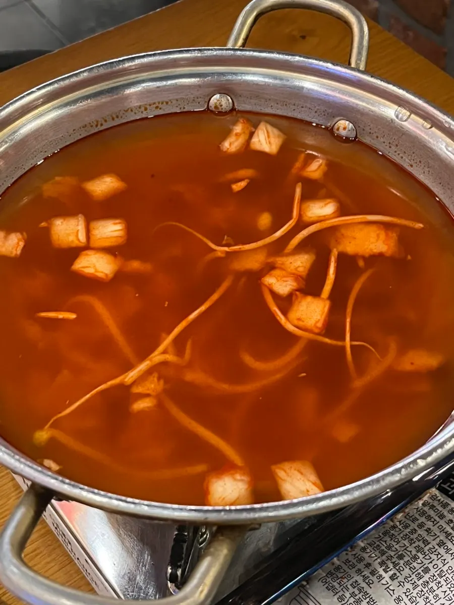Adding fresh noodles to the kimchi kalguksu