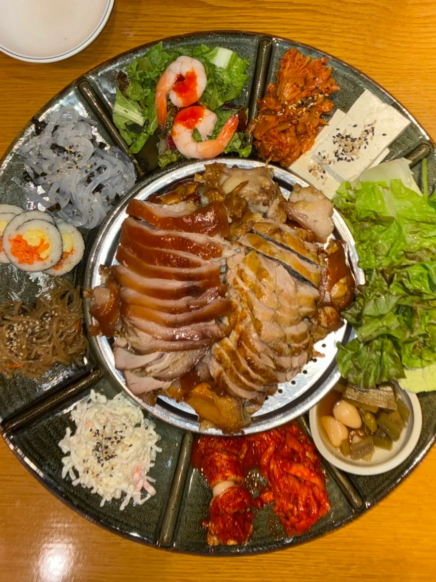 윤기 흐르는 족발과 둘러싼 반찬 접시
