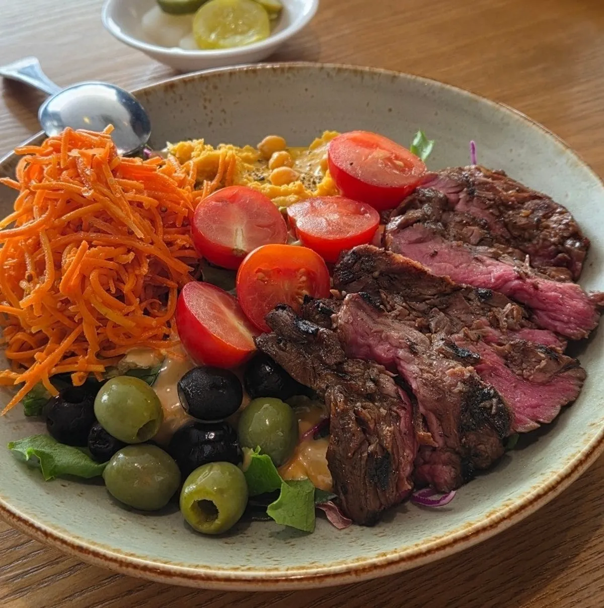 Steak plate served with carrots, tomatoes, and olives