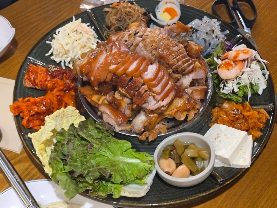 Side dish spread with lettuce, tofu kimchi, and mukbap at Miss Jokbal