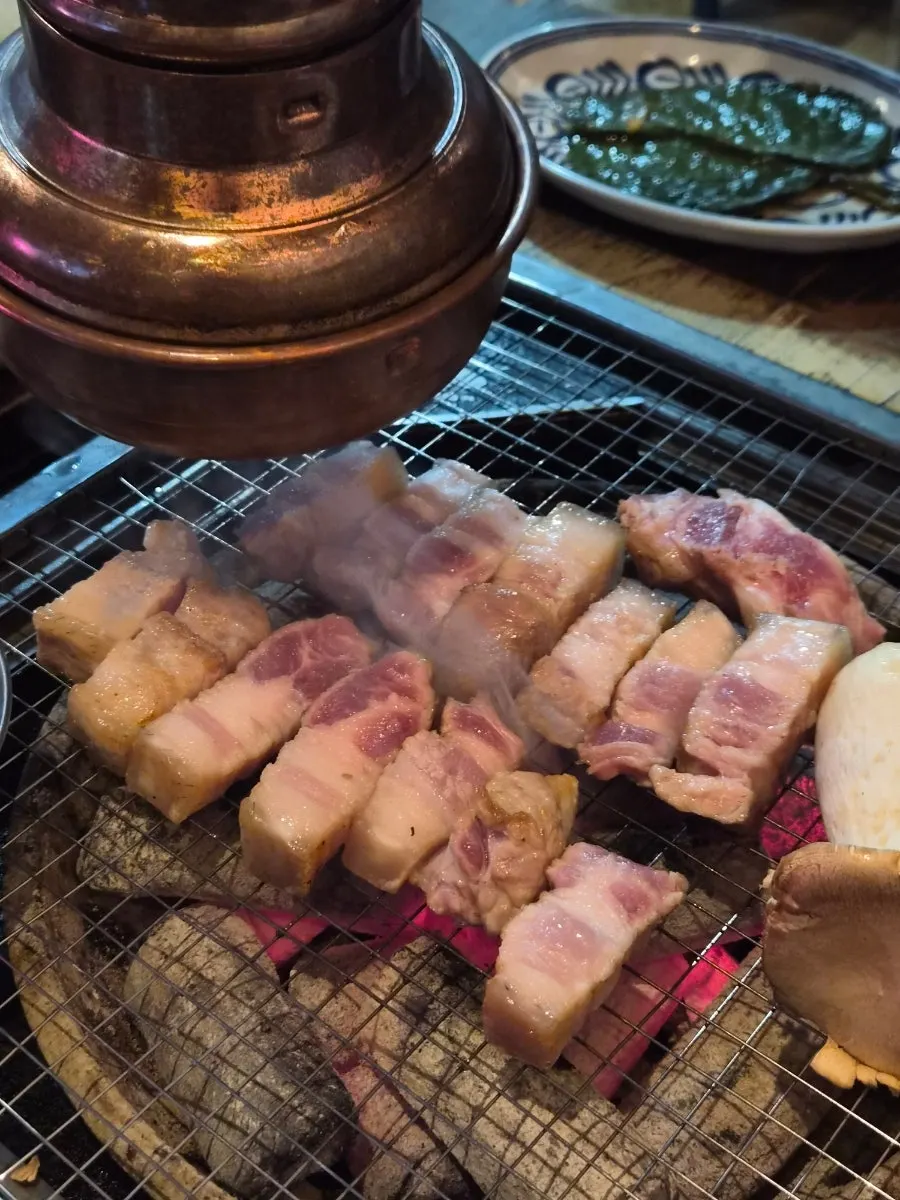 Black pork yukgyeopsal cooking on the grill