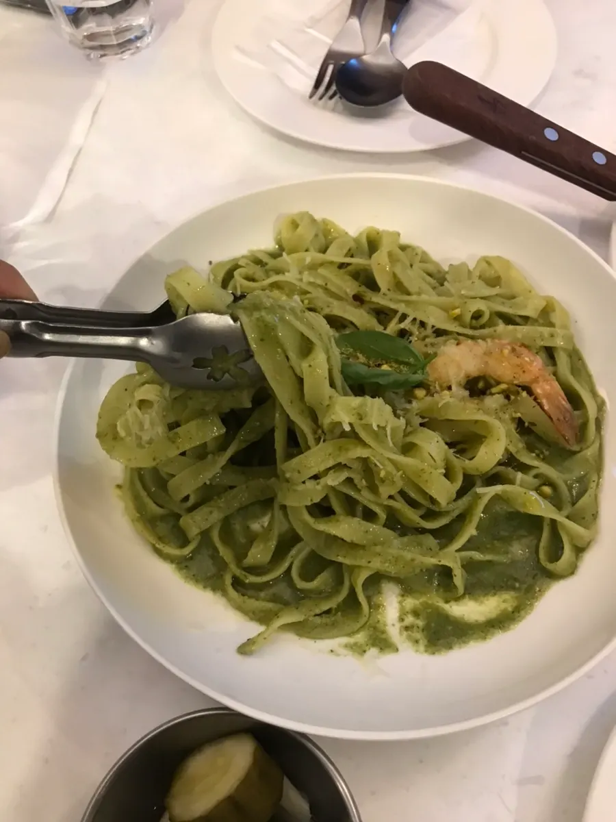 Close-up of basil pesto pasta topped with shrimp