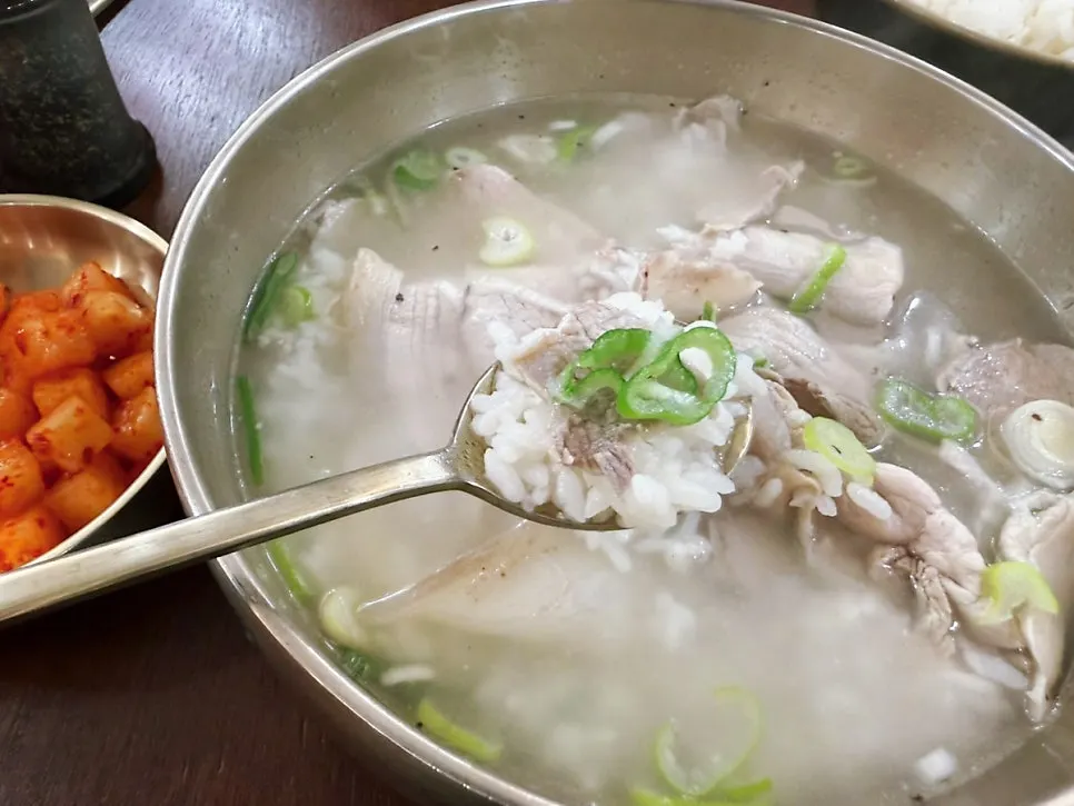 숟가락으로 떠올린 돼지곰탕 국물과 고기