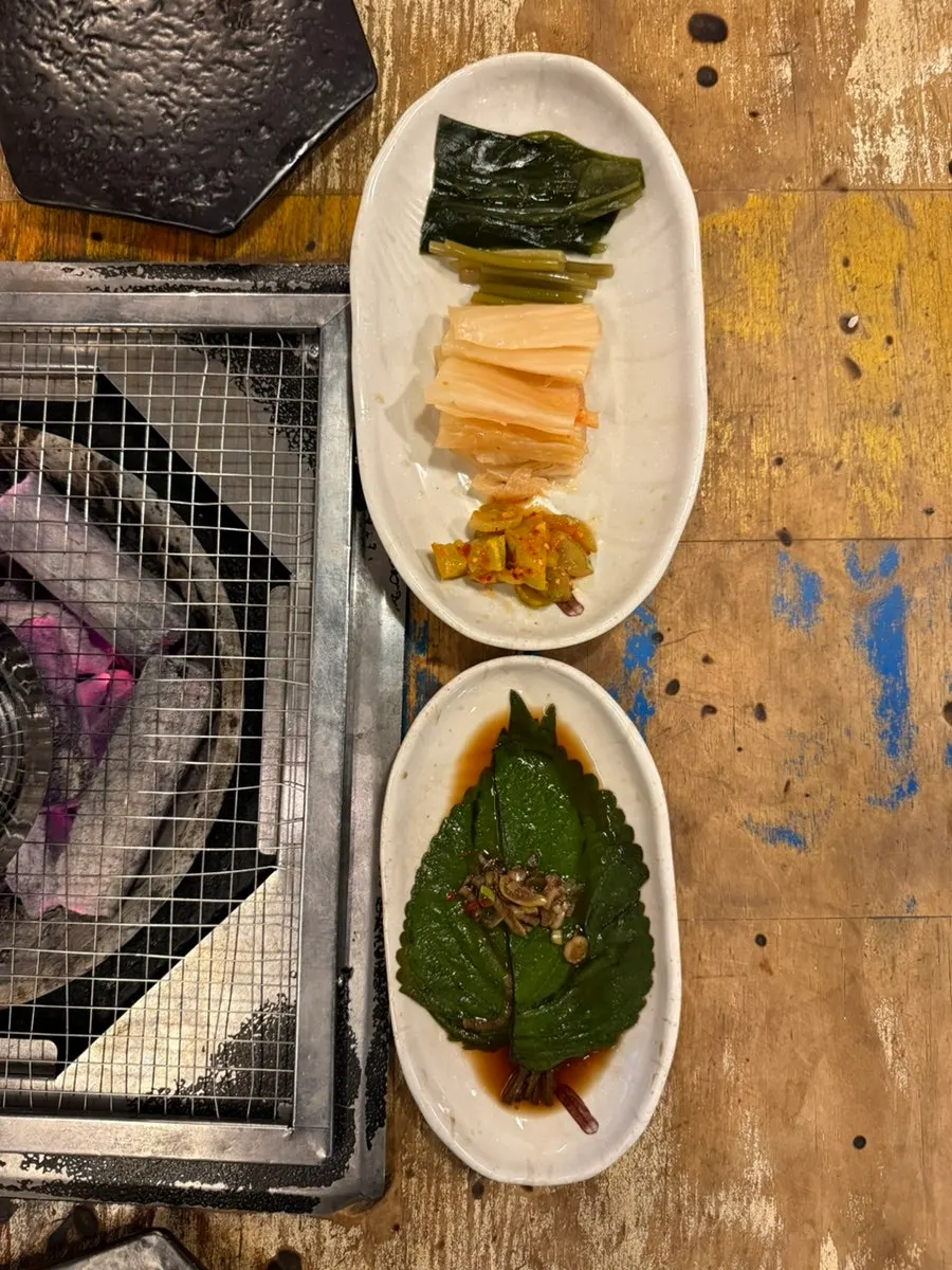 Side dishes including mountain garlic leaves, pickled perilla leaves, and aged kimchi