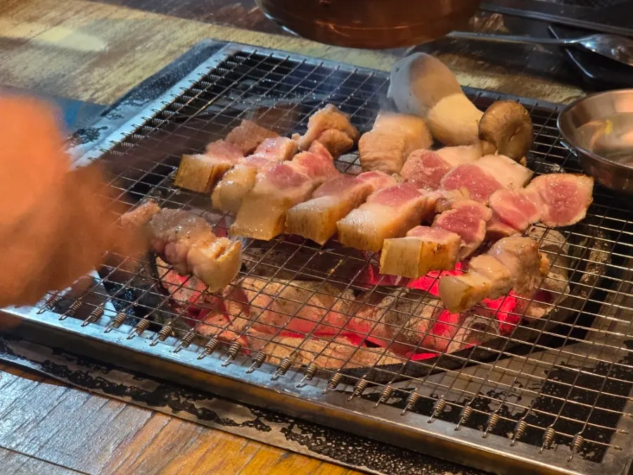 직원이 구워주는 오겹살 숯불구이 장면