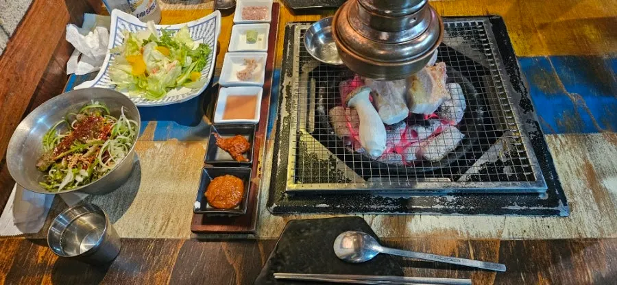 고기와 함께 차려진 샐러드와 밑반찬 상차림