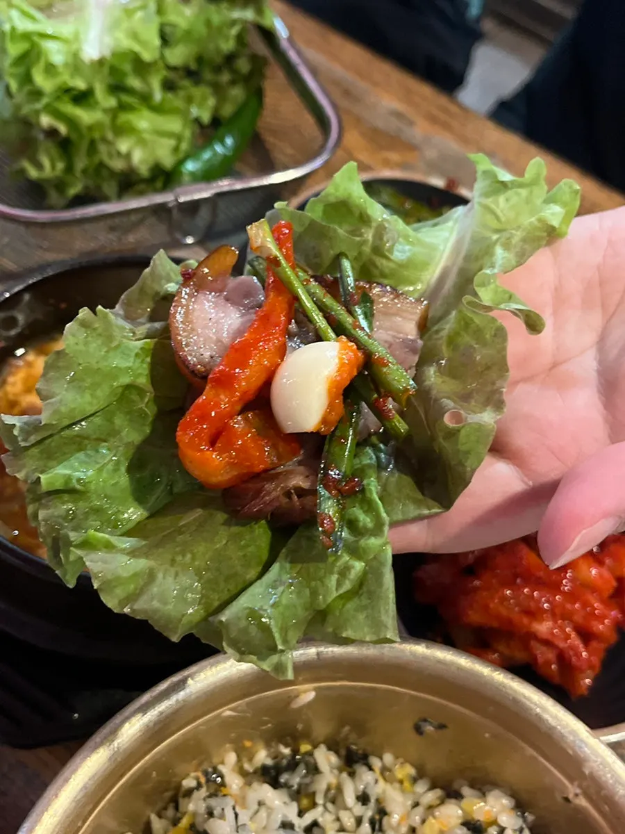 A piece of wood-fired jokbal meat picked up with chopsticks