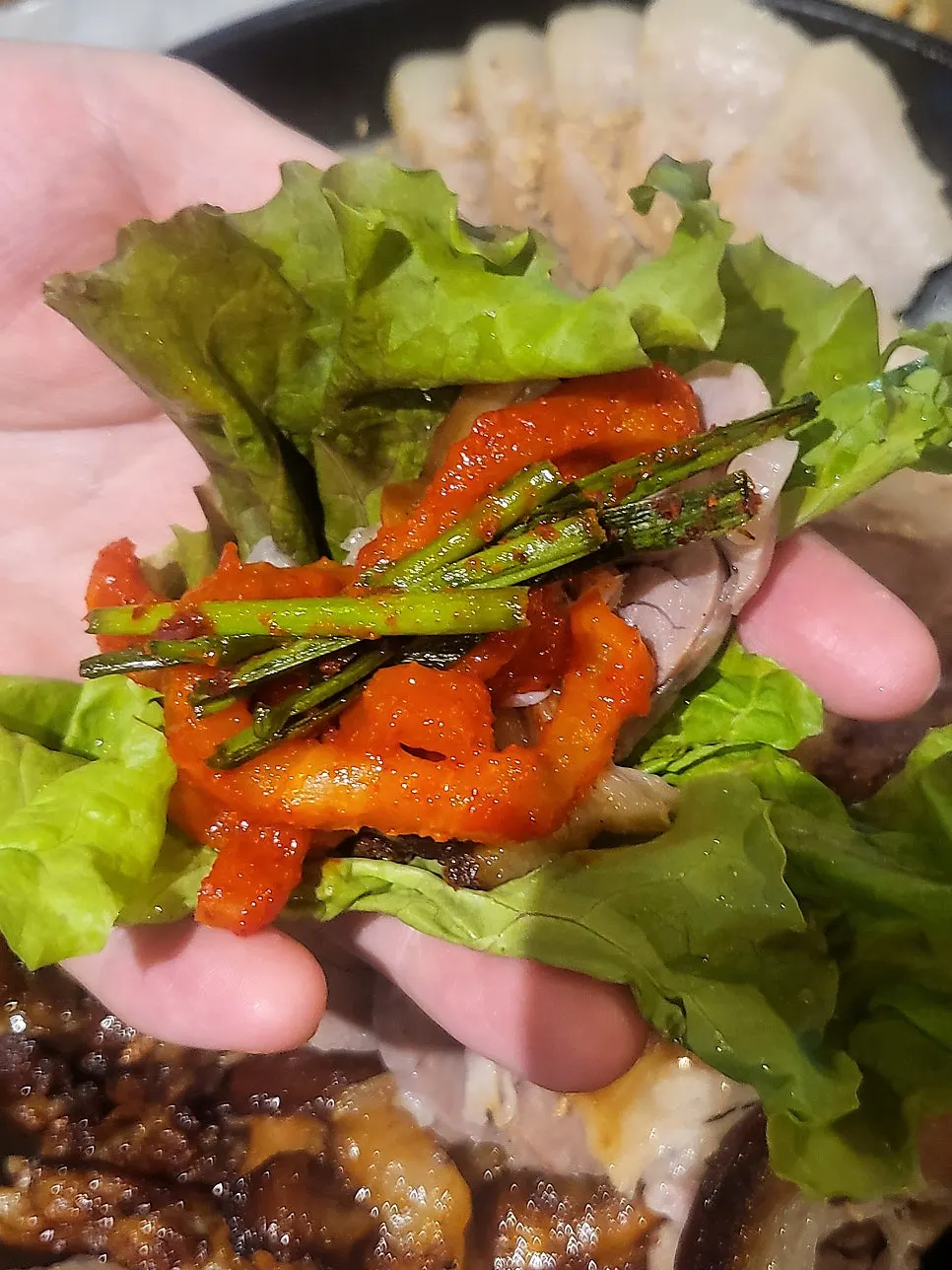 Piece of wood-fired jokbal topped with chive salad