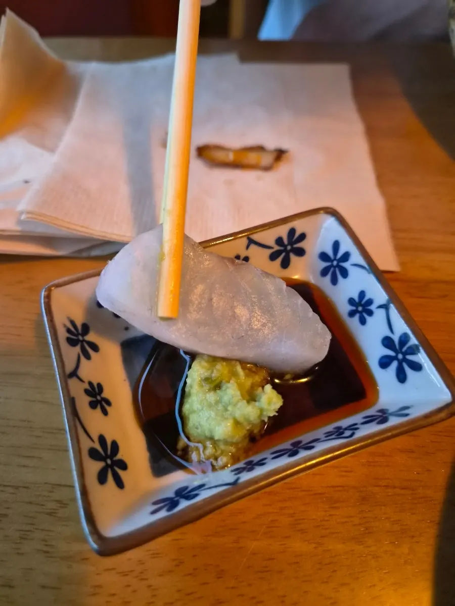 A piece of aged sashimi picked up with chopsticks