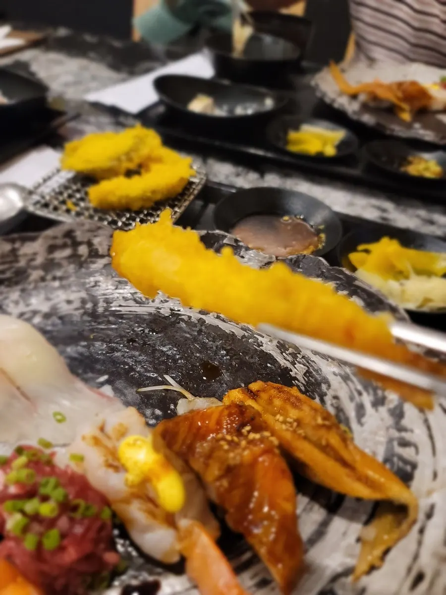 A plate of three tempura pieces including pumpkin and eggplant
