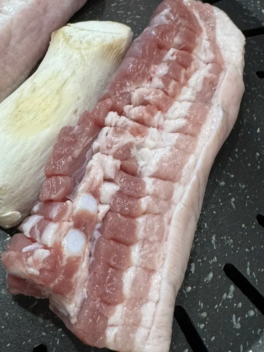 Black pork belly turning golden on the grill