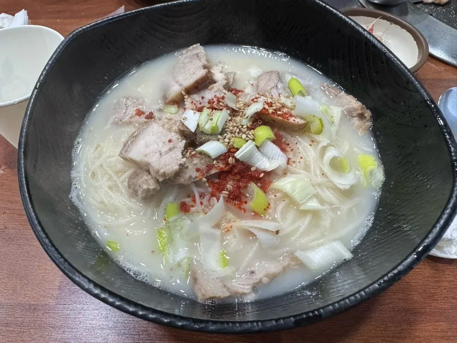 A bowl of Jeju pork noodle soup topped with pork