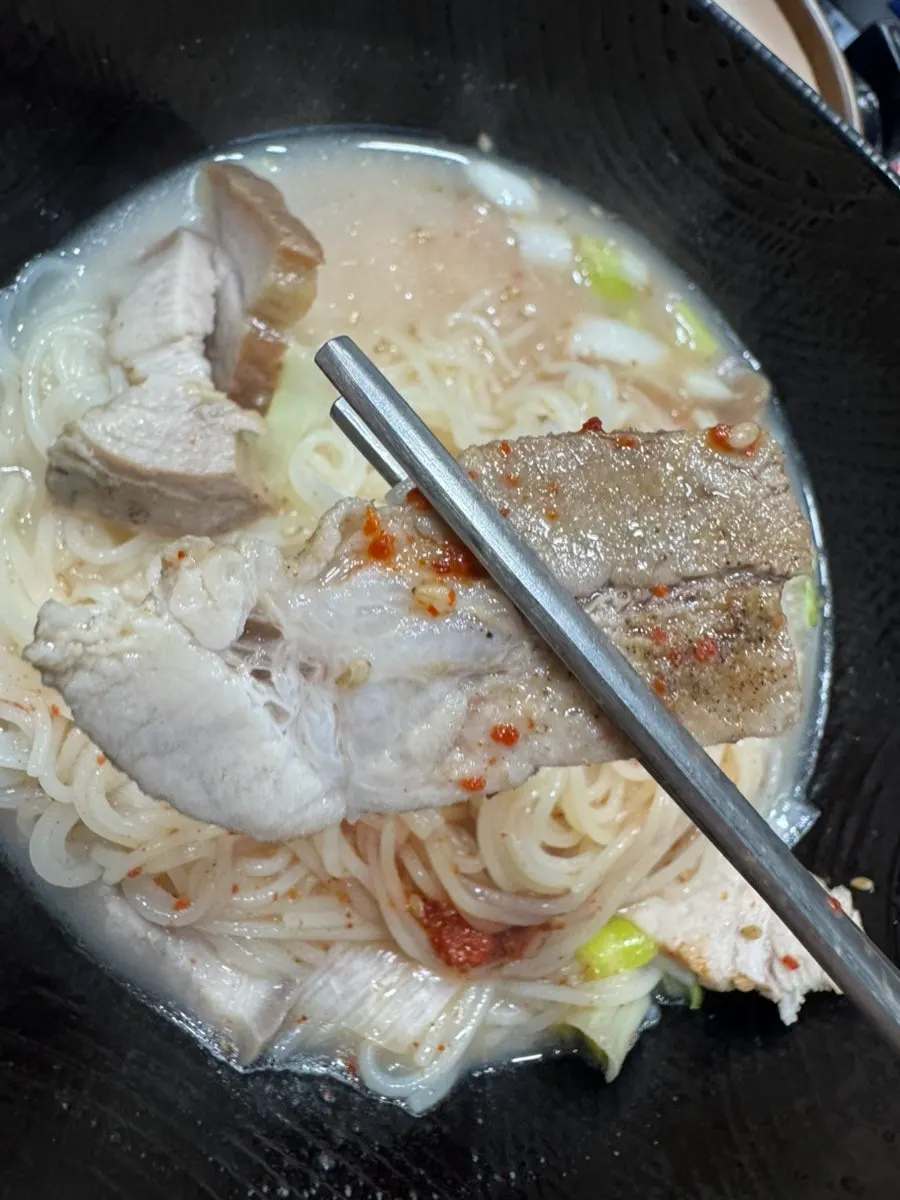 Table setting with pork noodle soup and pork belly together