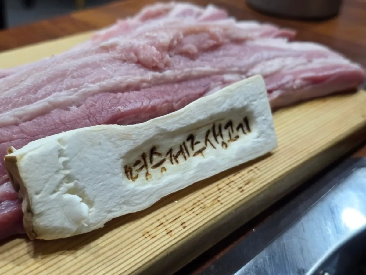Plate of mushrooms stamped with the restaurant name, alongside pork belly
