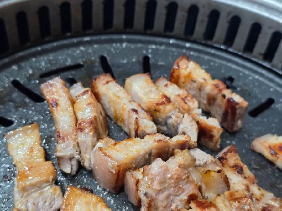 Table view of pork belly on the grill with kimchi stew