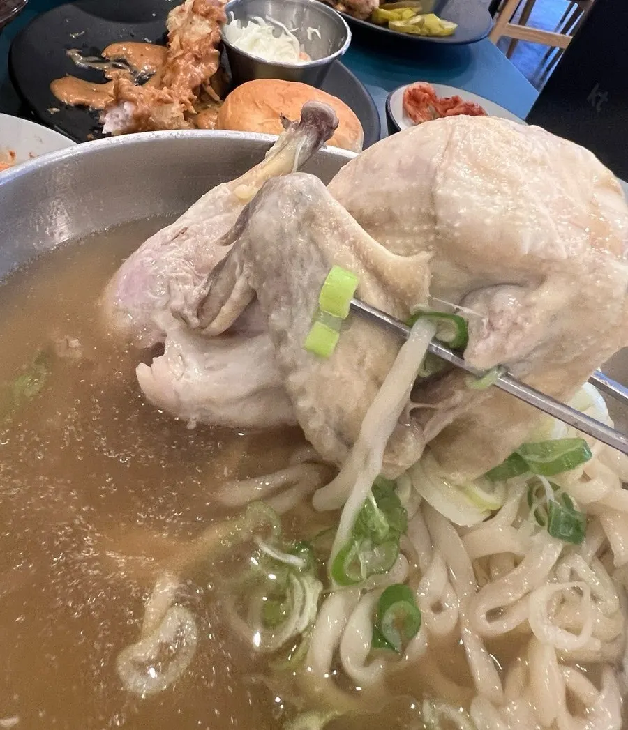 A large chicken drumstick lifted out of the kalguksu