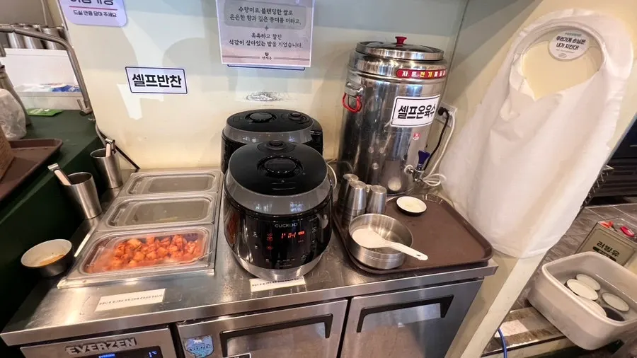 Rice and kimchi laid out at Myeongyeok's self-serve bar