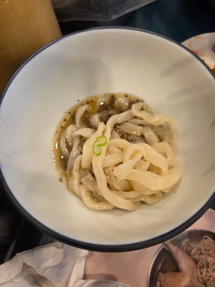Lifting up a bite of the kalguksu noodles