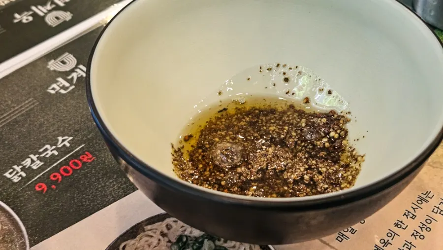 Dipping the kalguksu chicken into sesame oil sauce