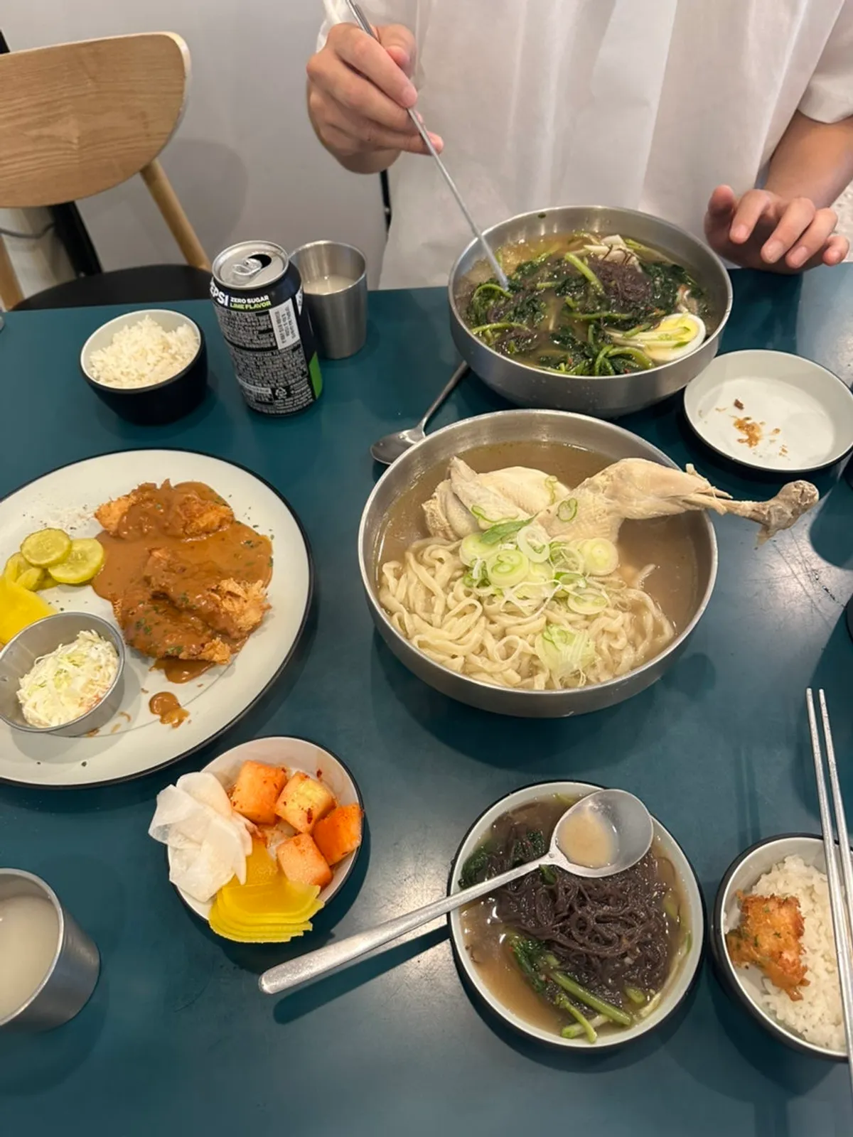 Table spread of half-chicken kalguksu, yeolmu naengmyeon, and chicken katsu
