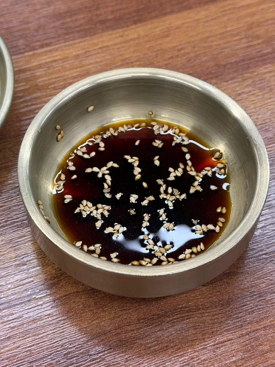 A piece of mul mandu dipped in soy sauce