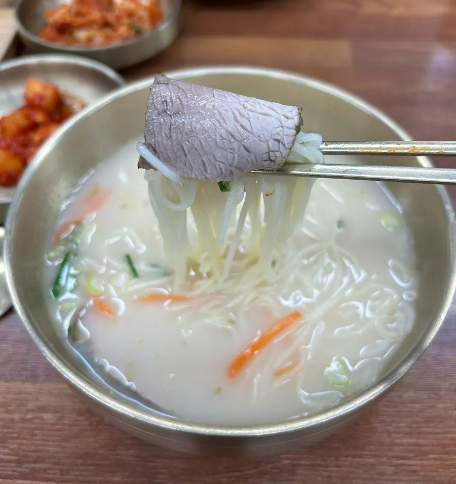 Chopsticks lifting medium noodles wrapped with black pork