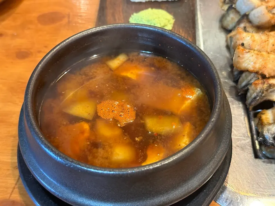 Table setting with doenjang jjigae, rice ball sushi, and oyster jeotgal