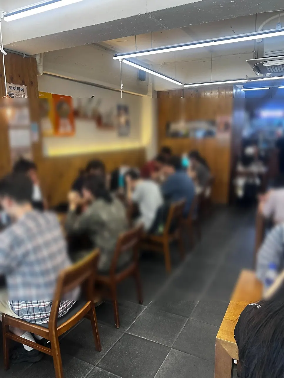 원목 테이블과 펜던트 조명이 있는 매장 홀 내부