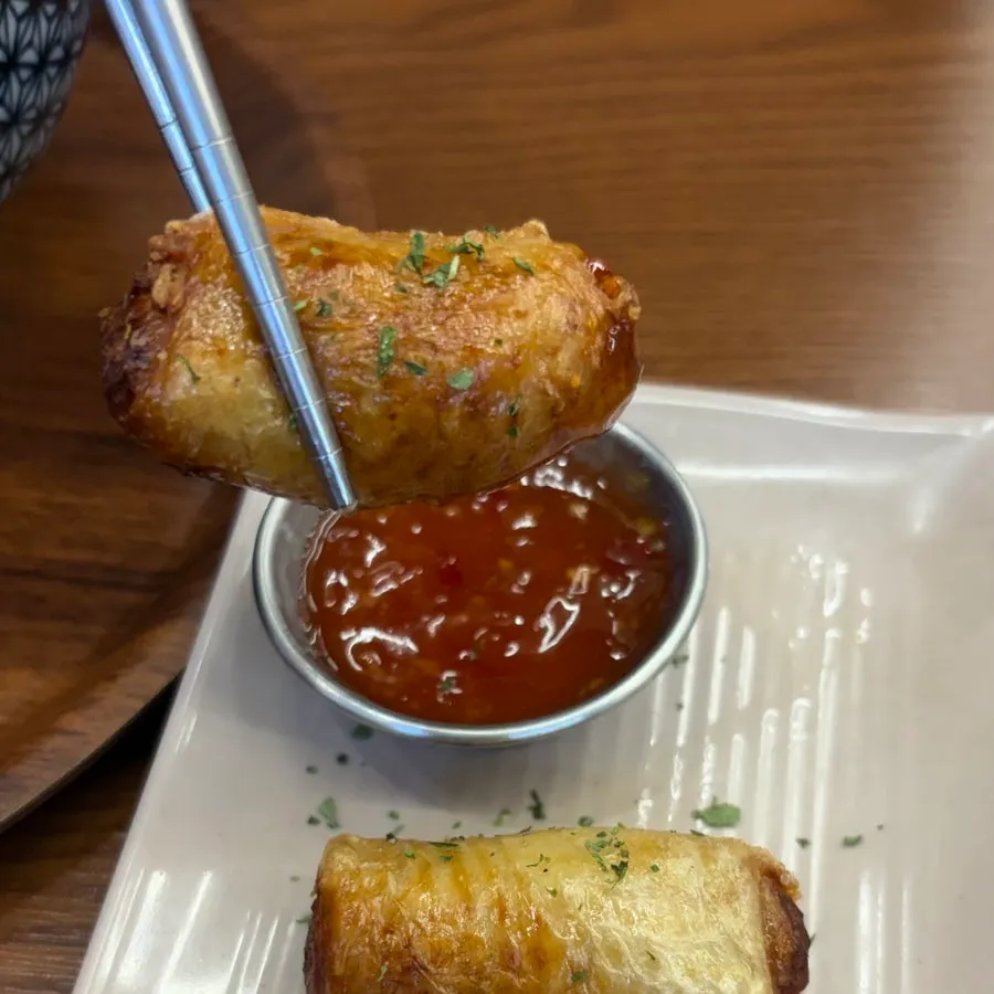 Cross-section of chicken skin gyoza dipped in sauce
