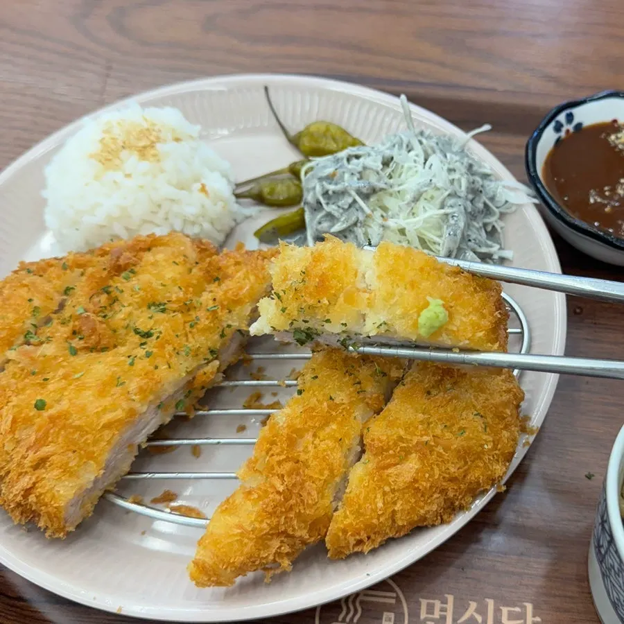 A piece of pork loin katsu dipped in sauce