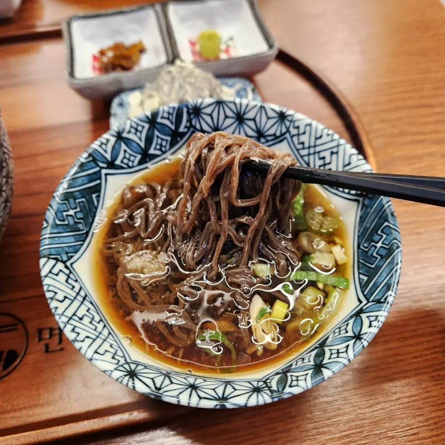 Cold soba noodles lifted with chopsticks