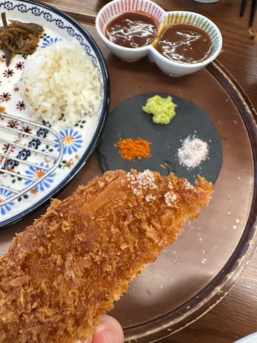 소스를 찍어 든 등심카츠 한 조각