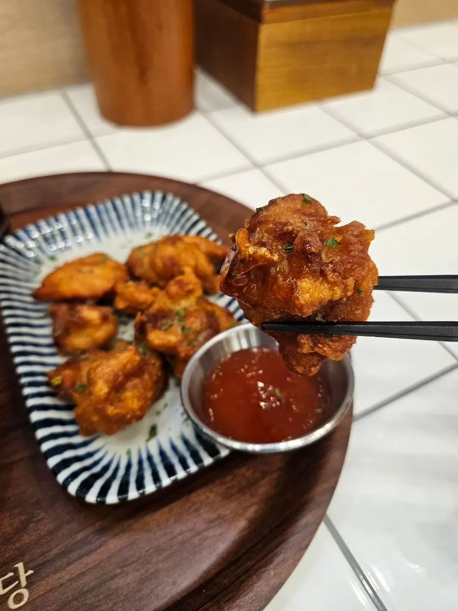 Karaage being dipped into sauce