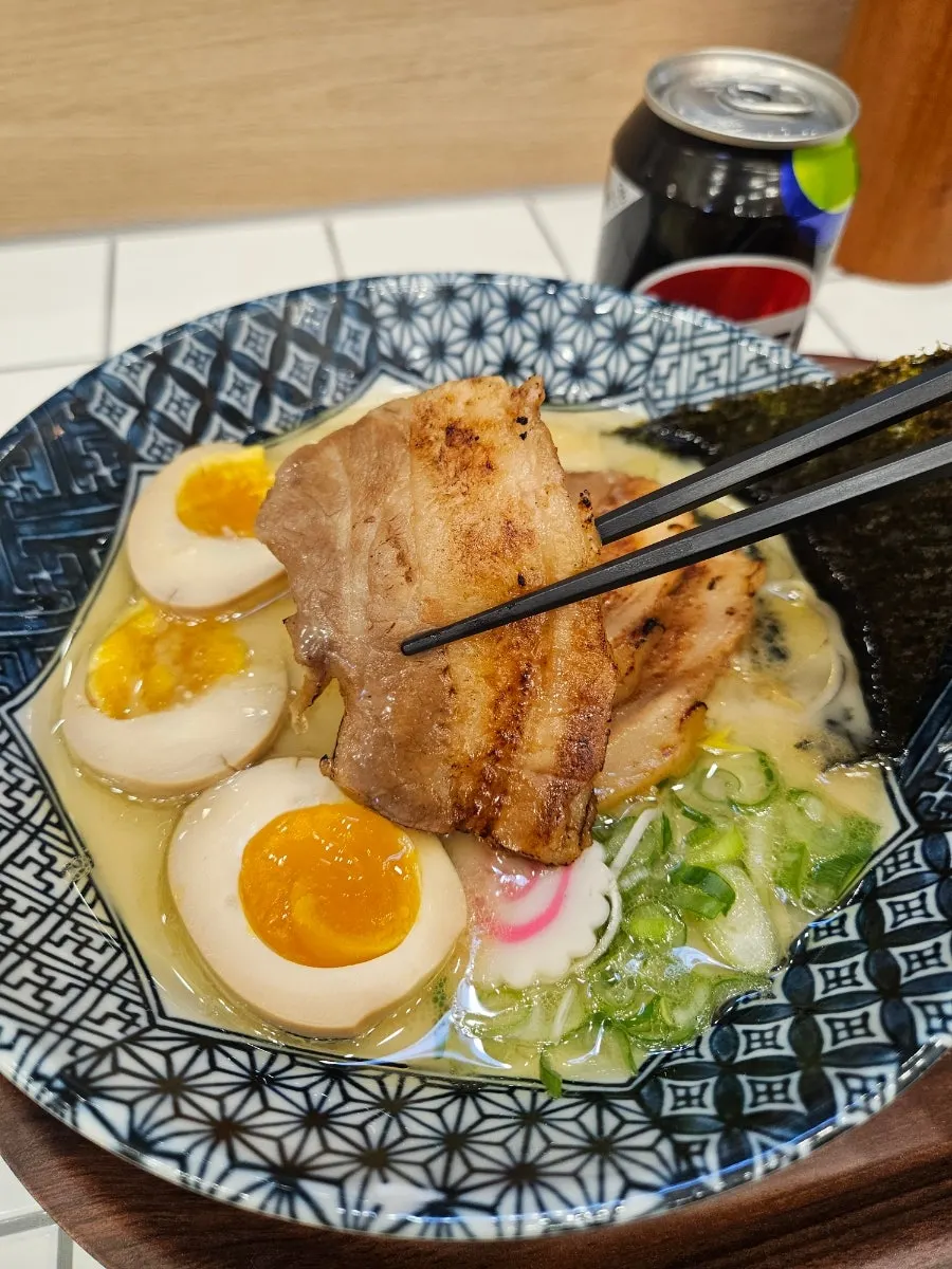Chopsticks lifting noodles from the tonkotsu ramen