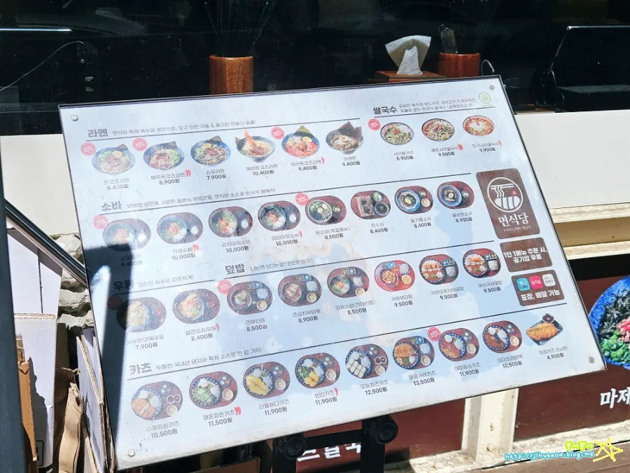 Large menu board with photos outside the restaurant