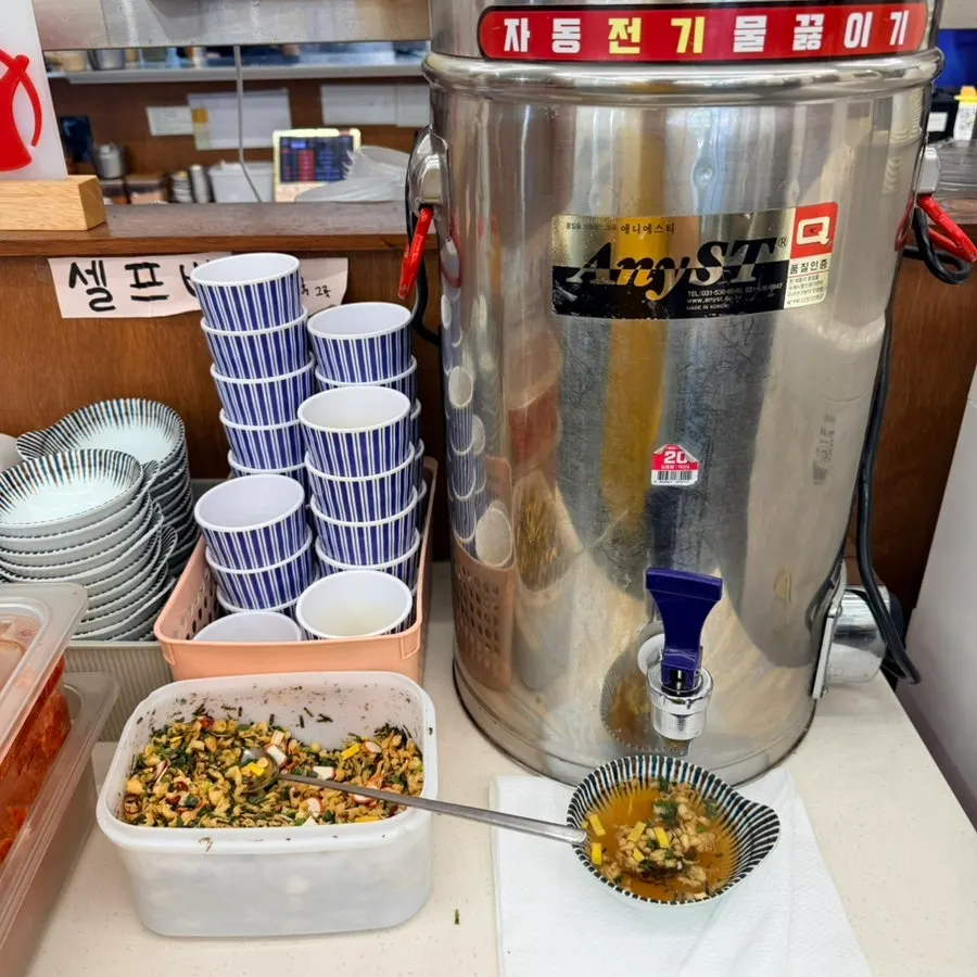Broth and kimchi side dishes at the self-serve bar