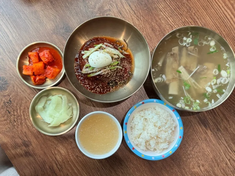 Table with bibim naengmyeon and soup dishes